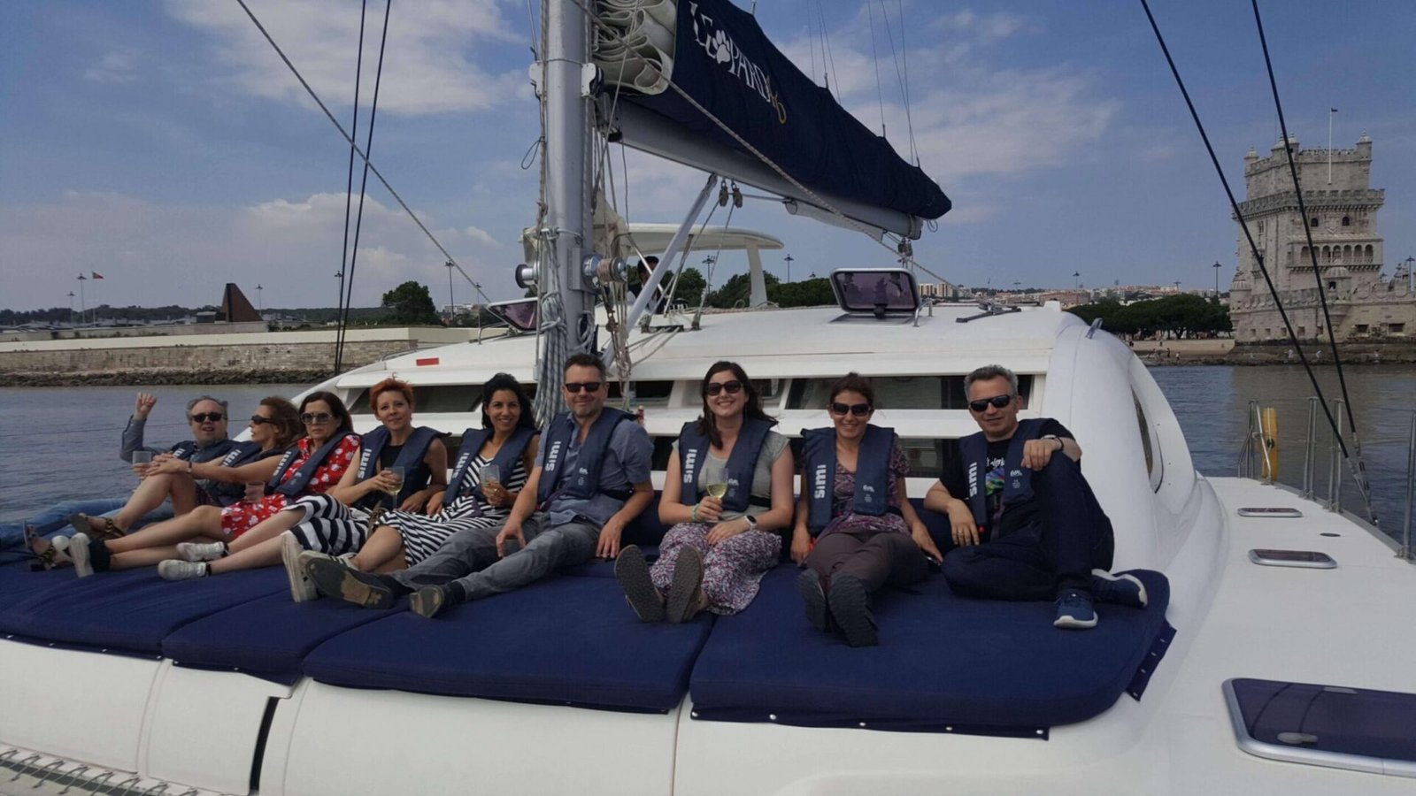 Des personnes assises à l’avant du catamaran avec la Tour de Belém en arrière-plan