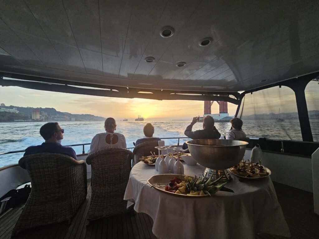 Pessoas sentadas no barco a tirar fotografias ao pôr do sol após a refeição