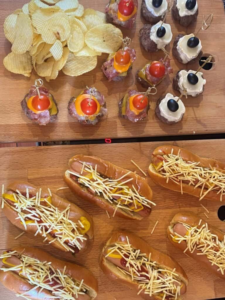 Gourmet catering table on board, with snacks such as mini hamburgers, handmade hot dogs, snacks and desserts by the glass. Ideal for private events or boat trips with catering included in Lisbon, providing a unique gastronomic experience on the Tagus River.