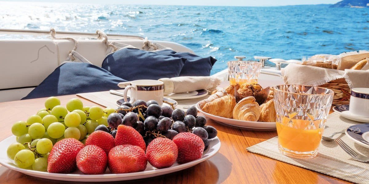 Fruits, croissant et jus d’orange servis à la table du bateau. Prêts à commencer la matinée avec ton brunch sur le fleuve